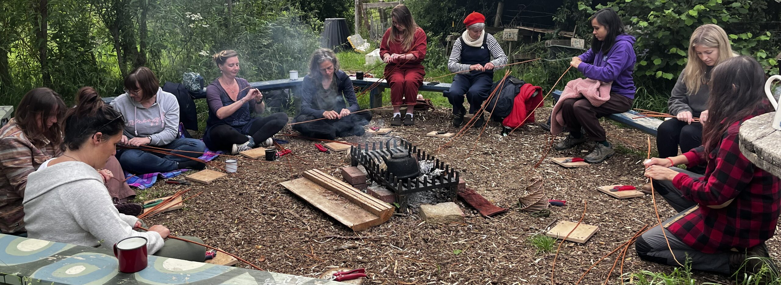 Group of women weaving willow around a campfire in the Mendip Hills